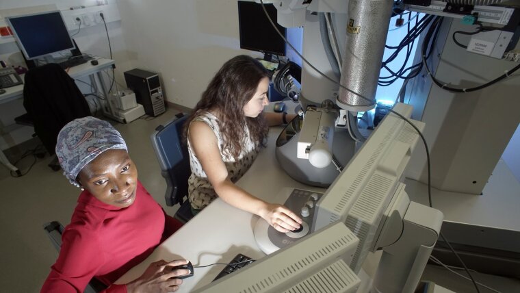 Two female chemists working on an electron microscope.