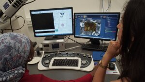 Two female chemists working on an electron microscope.