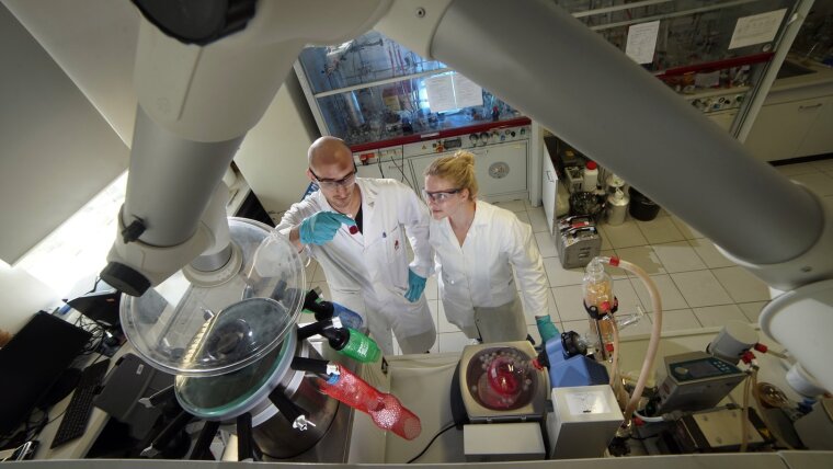 A female and a male chemist working in the synthesis lab.