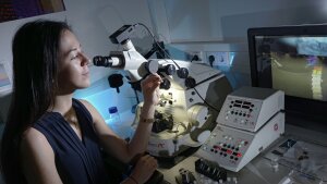 A female chemist at work on a microscope.